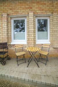 eine Terrasse mit 2 Stühlen, einem Tisch und 2 Fenstern in der Unterkunft Vėjūnė in Pervalka