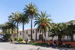 a group of palm trees in front of a building at Home2Book Vintage American Deluxe La Laguna in Las Lagunas