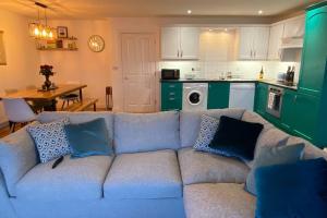 a living room with a blue couch and a kitchen at Island Dhu View - Seaside Penthouse in Portrush in Portrush