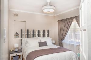 a white bedroom with a large bed and a window at Whale-Inn in Durban