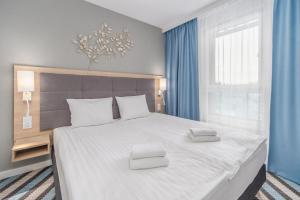 a bedroom with a large white bed with blue curtains at Sunny Apartments in Bel Mare Resort by Renters in Międzyzdroje