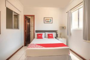 - une chambre avec un grand lit blanc et des oreillers rouges dans l'établissement OYO Hotel Diamante Negro - Salvador, à Salvador