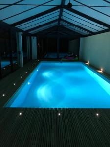 a swimming pool with blue lighting in a building at Chez sandrine in Mouhet
