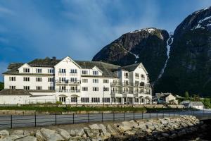 Vøringfoss Hotel في إيدفيورد: مبنى أبيض كبير أمام جبل