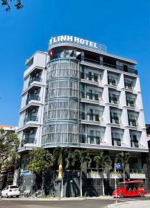 a tall white hotel with a palm tree in front of it at Y Linh Hotel in Quy Nhon