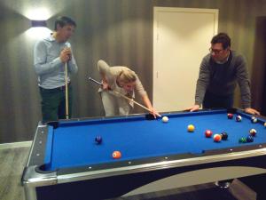 eine Gruppe von drei Personen, die eine Partie Billard spielen in der Unterkunft Charmehotel Kruishof in Ostende