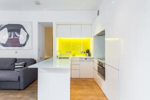 a kitchen with white cabinets and a yellow accent wall at Oxford Circus Designer Apartment in London