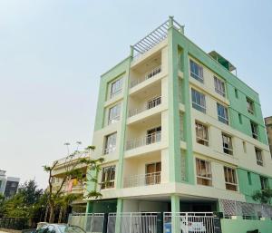 un edificio verde y blanco con un coche aparcado delante de él en BluO Lake Facing 1BHK NewTown, Terrace Garden, Gym, en Calcuta