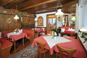 une salle à manger avec des tables et des chaises rouges dans l'établissement Gästehaus Bartholomäus, à Oberwössen