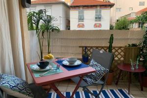 une table et des chaises roses sur un balcon avec une table et un bol de fruits dans l'établissement Bel appartement à 100 mètres de la plage, à Nice