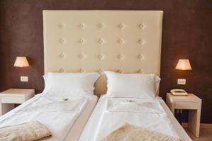 a bedroom with two beds with white sheets and two lamps at HOTEL ASTOR in Limone sul Garda