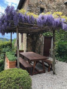 una mesa de picnic con glicinas púrpuras colgando sobre ella en Corzano e Paterno en San Casciano in Val di Pesa