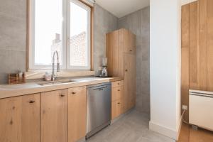 a kitchen with wooden cabinets and a sink and a window at Lou Le Lavandou in De Panne