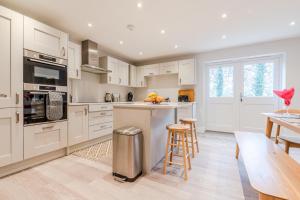 a kitchen with white cabinets and a bar with stools at Maple House in Chipping Campden
