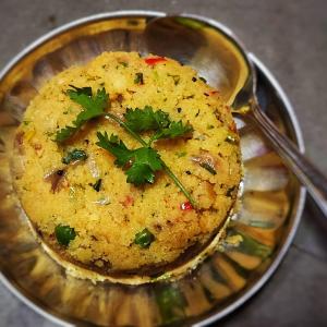 a bowl of food with a sprig of cilantro at Chandraprabha Nyahari Niwas in Malvan