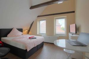 a bedroom with a bed and a desk with a laptop at Gaestehaus Dorum 04 in Dorum
