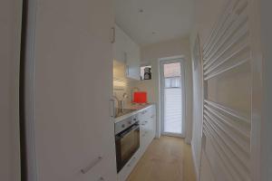 a white kitchen with a sink and a stove at Strandlaeufer NS6 Wremen in Wremen