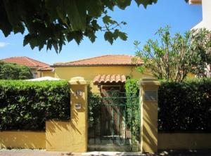 uma casa amarela com um portão e arbustos em Villino ida em Follonica