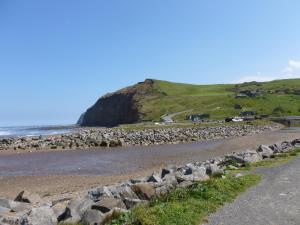 a road next to a beach with a cliff at Griff Cottage, Skinningrove in Skinningrove