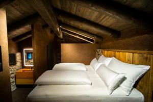 Schlafzimmer mit einem Bett mit weißer Bettwäsche und Kissen in der Unterkunft Les Pardines 1819 Mountain suites & SPA in Encamp