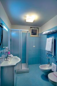 niebieska łazienka z 2 umywalkami i prysznicem w obiekcie Aurea Hotel w mieście Tortoreto Lido