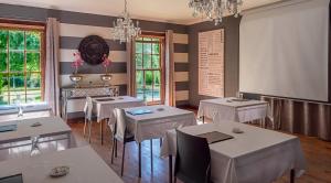 a dining room with white tables and chairs and chandeliers at Kakamas Hotel in Kakamas