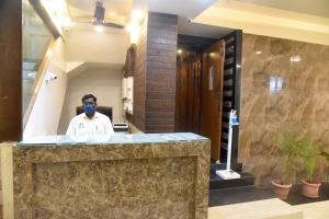 mężczyzna w masce twarzy w holu w obiekcie Hotel Parag w mieście Pune
