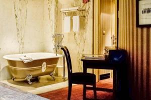 a bathroom with a tub and a desk and a chair at Hôtel du Romancier in Paris +20 photos