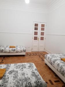 two beds in a room with white walls and wooden floors at Rainbow Guest House in Lisbon