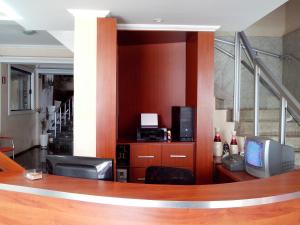 a lobby with a desk with a television and a staircase at Lelis Hotel in Itapira