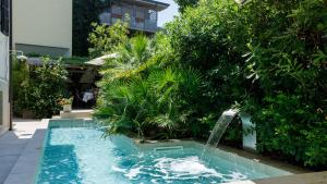 a swimming pool with a fountain in a garden at VILLA CORONA 8, Emma Villas in Cattolica