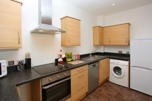 a kitchen with wooden cabinets and a washer and dryer at Parkes Court Apartments in Telford