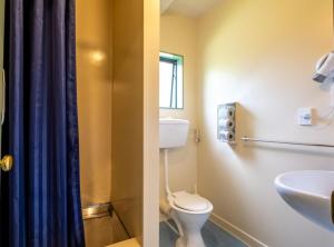 a bathroom with a toilet, sink, and bathtub at Kakapo Lodge in Hanmer Springs