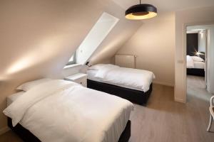 a bedroom with two beds and a staircase at Domein Lepelem in De Haan
