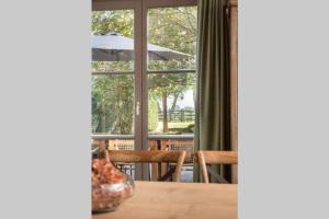 a table with chairs and an umbrella in front of a window at Domein Lepelem in De Haan