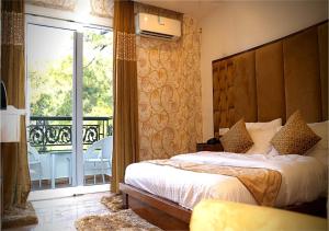 a bedroom with a large bed and a balcony at Hotel Saheb's Castle McLeodganj in McLeod Ganj