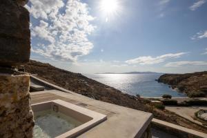 a building with a bath tub next to the water at Phos Villas Tinos in Agios Romanos