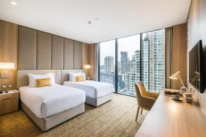 a hotel room with two beds and a large window at SKYVIEW Hotel Bangkok - SHA Extra Plus in Bangkok