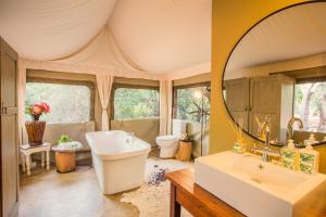a bathroom with a tub and a sink and a mirror at Zwartkloof Adventures Tented Camp in Bela-Bela