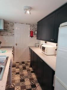 a kitchen with black cabinets and a white microwave at Sunrise Cottage in Lowestoft