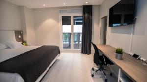 a bedroom with a bed and a desk with a computer at Hotel Ciudadela Pamplona in Pamplona