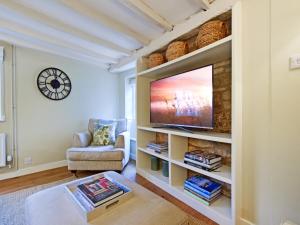 een woonkamer met een flatscreen-tv op een plank bij Thatch Cottage in Todenham