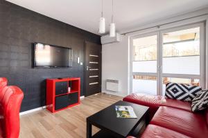 a living room with a red couch and a tv at Victus Apartamenty, Apartament Villa Sunrise in Sopot