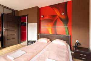 a bedroom with a bed with a painting on the wall at Victus Apartamenty, Apartament Villa Sunrise in Sopot