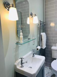 ein Badezimmer mit Waschbecken und Spiegel in der Unterkunft Garden Flat in Charmouth + 19 Fotos