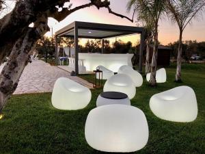 un groupe de chaises blanches assises dans l'herbe dans l'établissement Terra dei Sogni, à Torre Lapillo