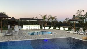 a swimming pool with white chairs and a table and a pool at Terra dei Sogni in Torre Lapillo
