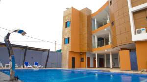a hotel with a swimming pool in front of a building at Hotel La Casa Cielo in Cotonou