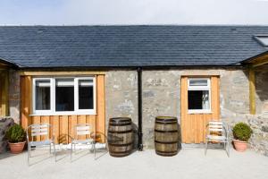 um grupo de cadeiras e barris em frente a um edifício em The Milking Sheds, Dufftown em Dufftown