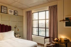 a bedroom with a bed and a window and a table at The Hoxton, Southwark in London